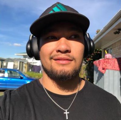 Jayde is outside on a sunny day wearing a cap and headphones.