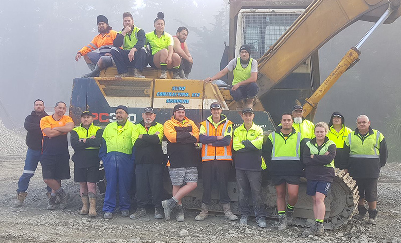 Eighteen workers in high visibility clothing around a digger.