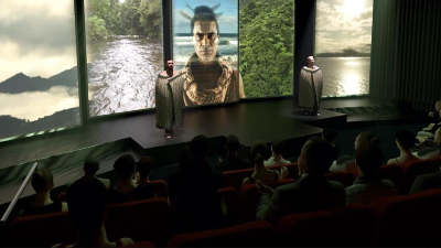 In a theatre setting two people are standing in wearing Māori garments in front of panels of images.