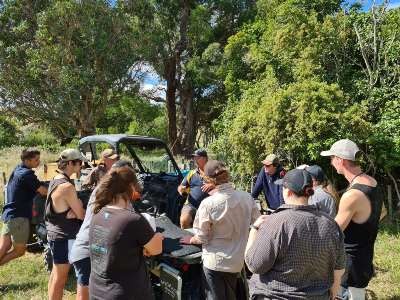 Rangatahi at a farm, standing around a quad bike listening to the trainer at their induction