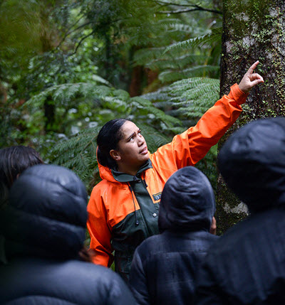Ranger Ataahua Kingi in a forest with a group of school children.