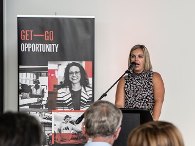 A person speaking at a podium. In the background is a Get-Go pull-down banner.