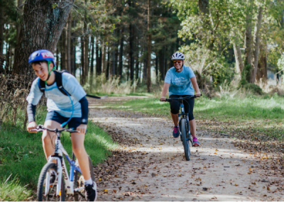 A couple of people are happily riding bikes on a trail.