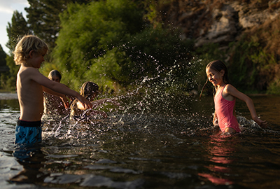 Two children are playfully splashing in a river.