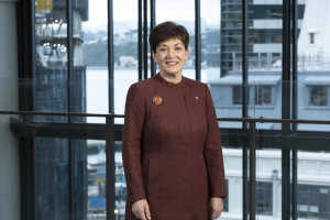 A mid shot of a woman with short, dark hair, wearing a maroon coloured dress.