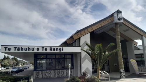 A modern marae style building with Māori designs on the exterior walls and around the entryway