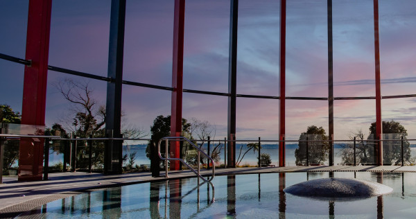 A modern indoor pool with windows all around the edge of the building