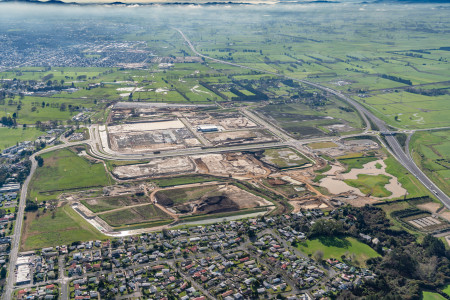 A bird's eye view shot of green and brown fields beyond a residential area.