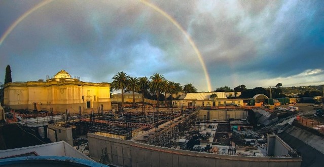 A rainbow over a construction site at sunset