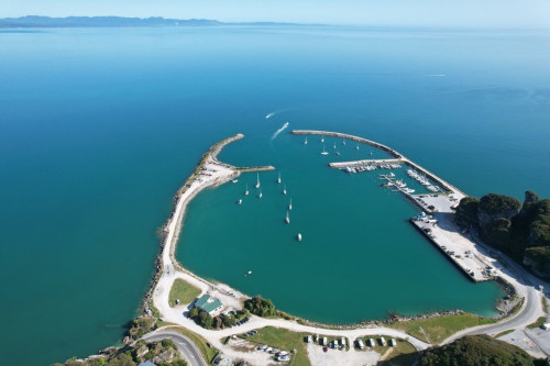Bird's eye view of the port, with strips of land curving around each side of it forming an inlet where boats are anchored